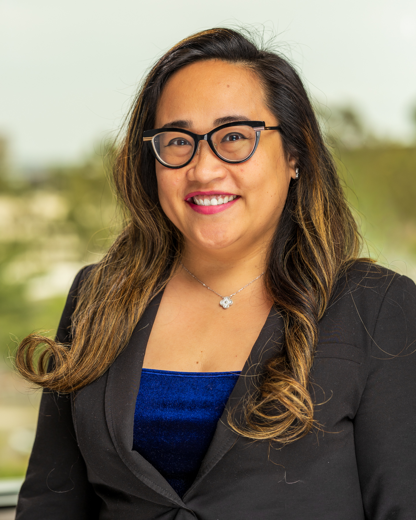 Smiling woman in glasses and black blazer outdoors