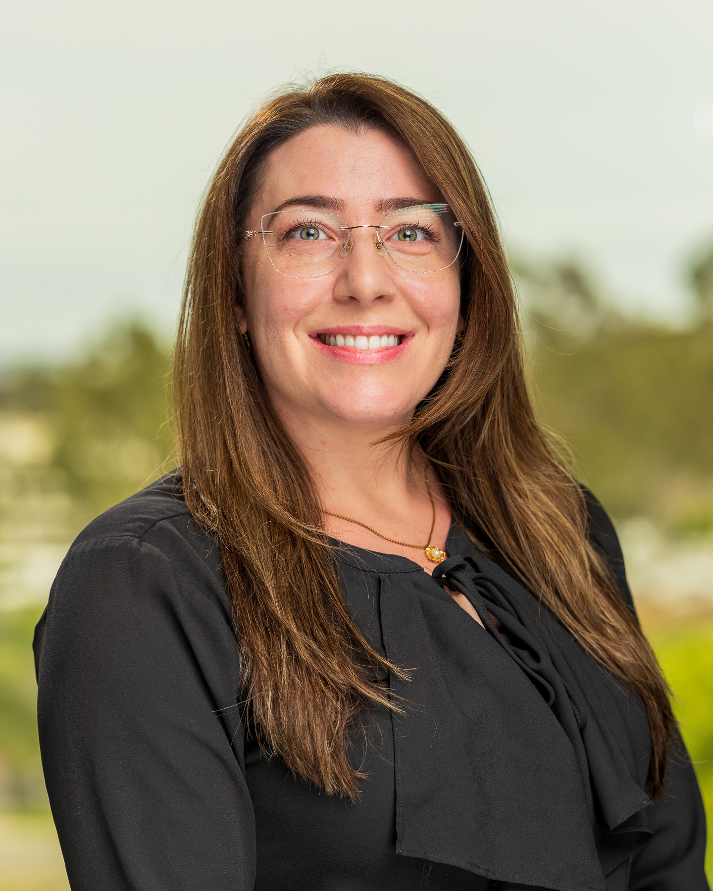 Smiling woman with glasses outdoors.