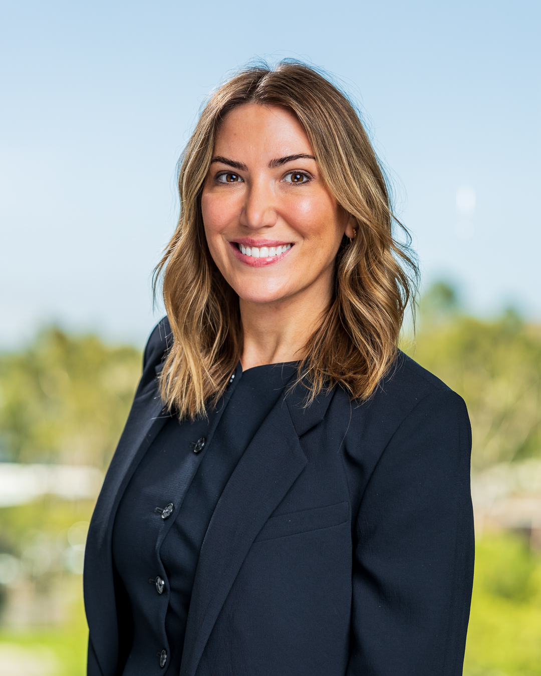 Smiling businesswoman in black blazer outdoors