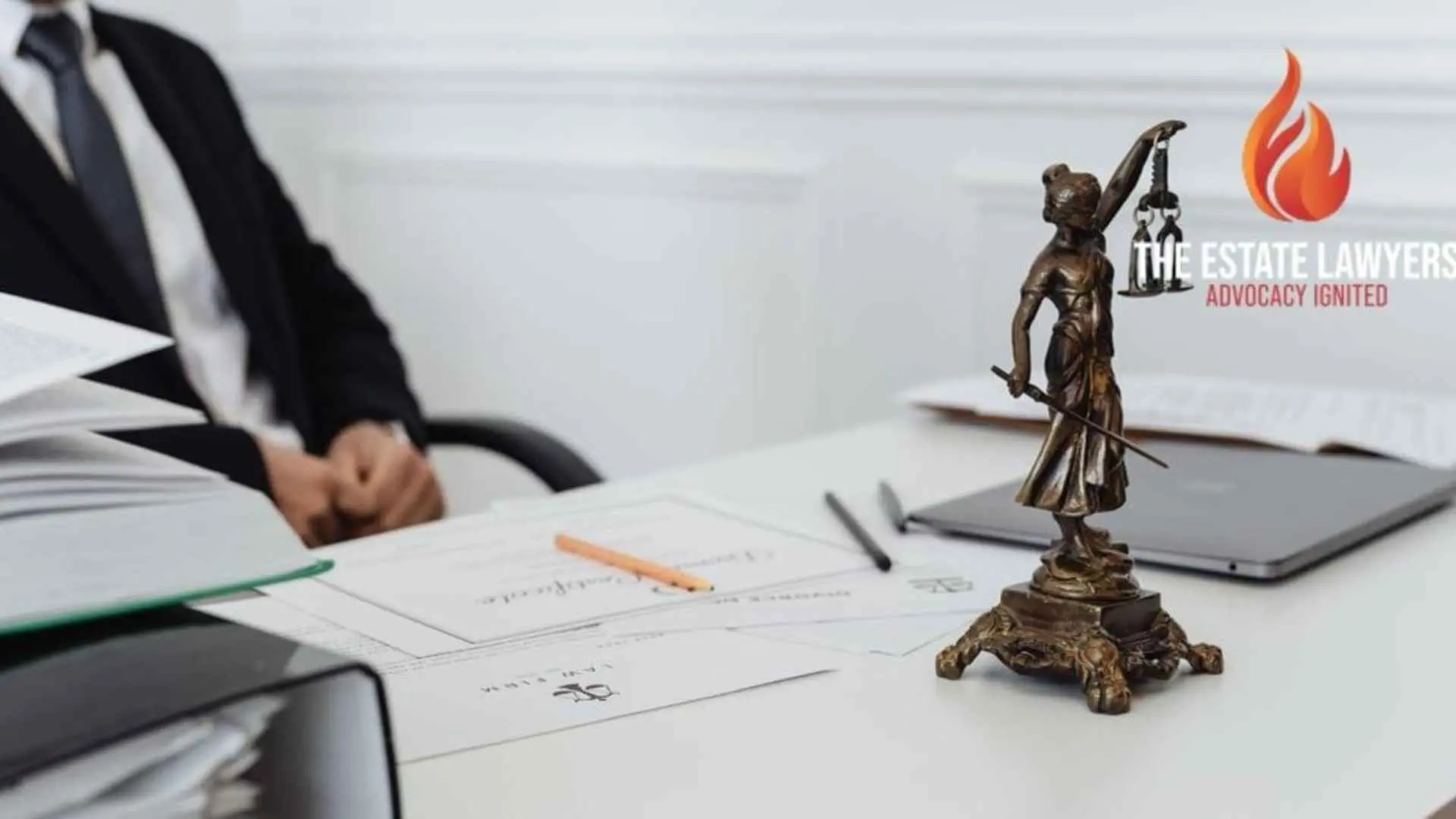 A legal professional's workspace featuring Lady Justice statue, documents, and a laptop, illustrating inheritance dispute attorneys in Fresno. Branded with the The Estate Lawyers, APC logo.